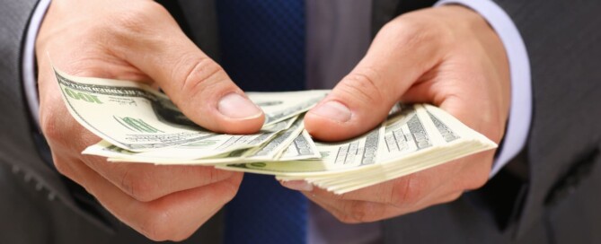 Man hold in arm pack of hundred dollar bills