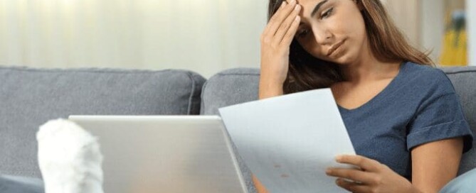 A lady having a headache reading insurance paperwork