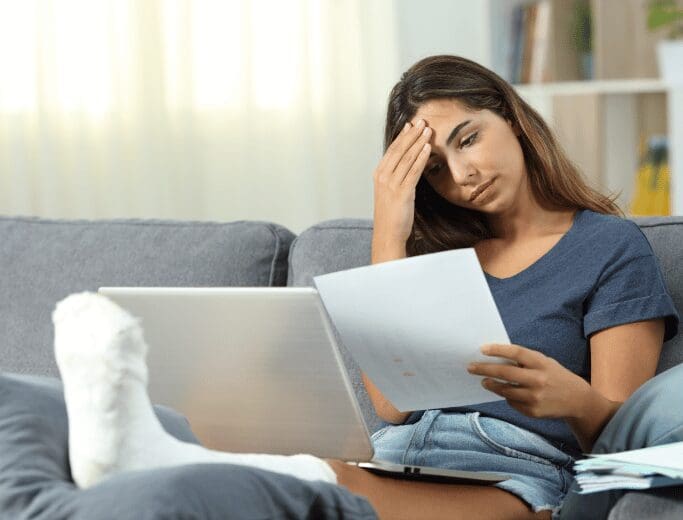 A lady having a headache reading insurance paperwork