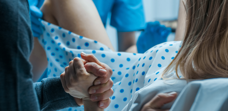 woman giving birth holding hand in delivery room