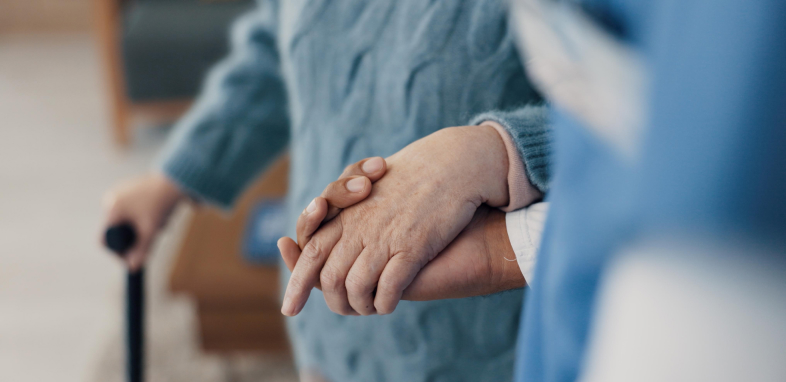 close up of elderly person holding hands with caretaker