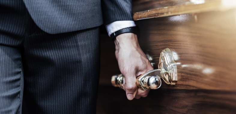 close up of man in suit holding casket handle